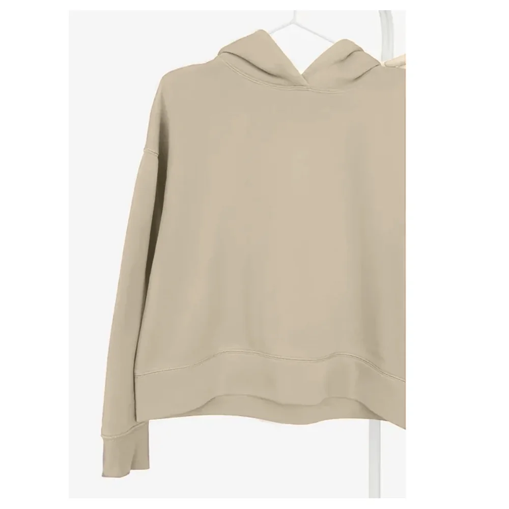 A heavyweight hoodie in stone, on a hanger against a white wall